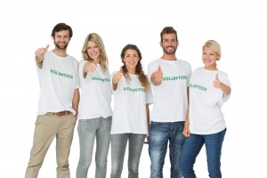 Group portrait of happy volunteers gesturing thumbs up over white background
